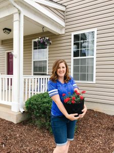 military wife holding fabric containers for gardening in front of military housing