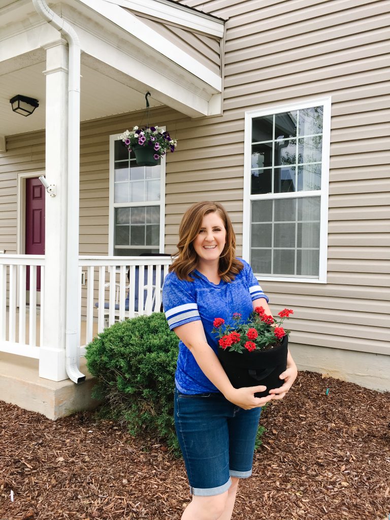 military wife holding fabric containers for gardening in front of military housing